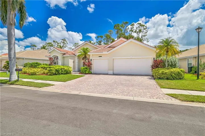 Mediterranean / spanish house with stucco siding, a front yard, an attached garage, decorative driveway, and a tile roof