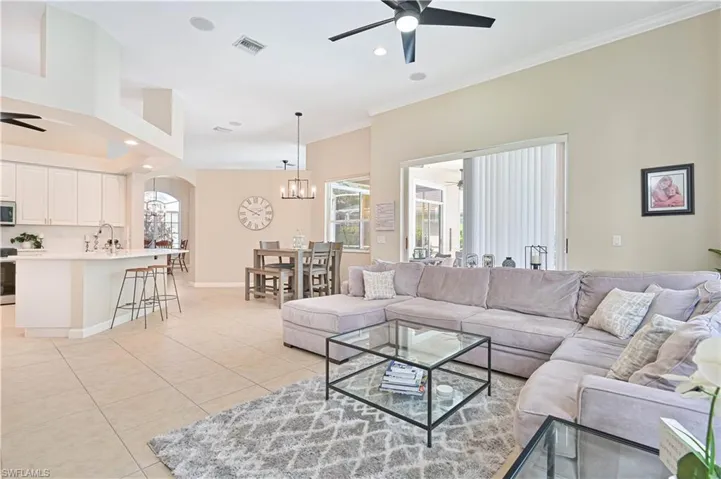 Living area featuring a ceiling fan, light tile patterned floors, crown molding, and suspended lighting