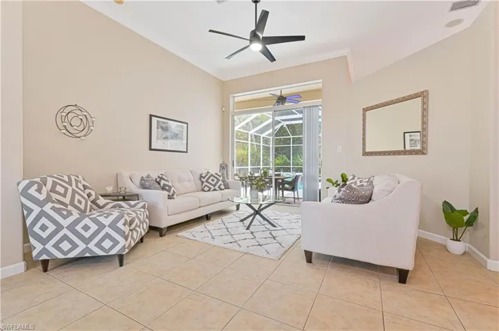 Living room featuring a sunroom, ornamental molding, light tile patterned flooring, and ceiling fan