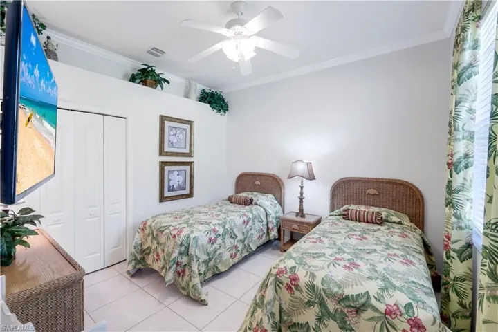 Bedroom with ornamental molding, ceiling fan, a closet, and light tile patterned floors