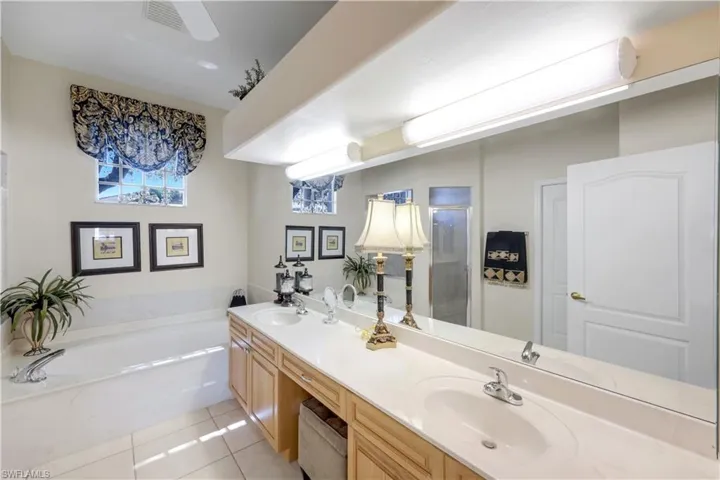 Master Bathroom with light tile patterned floors, a bath, double vanity, and a stall shower