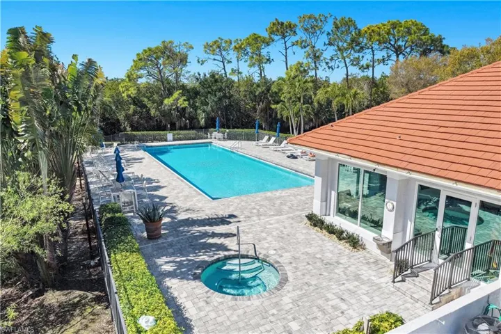 Community pool with a patio, view of scattered trees, and a community hot tub