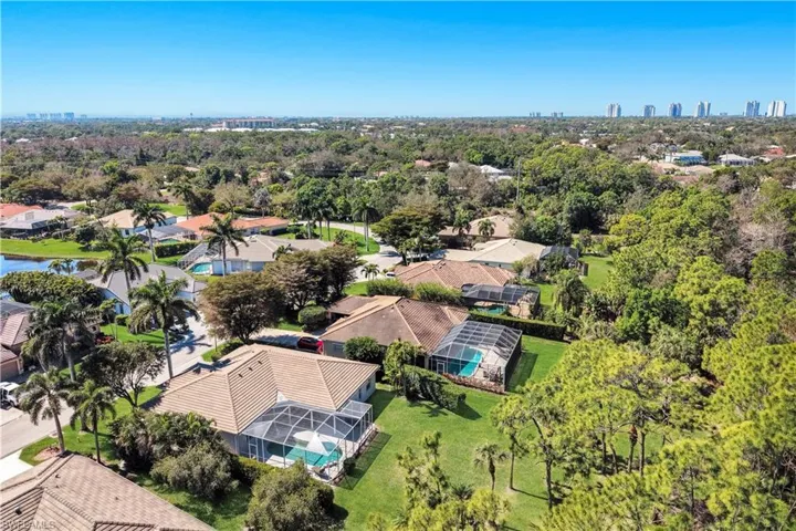 Aerial perspective of suburban area featuring city skyline and a tree filled landscape