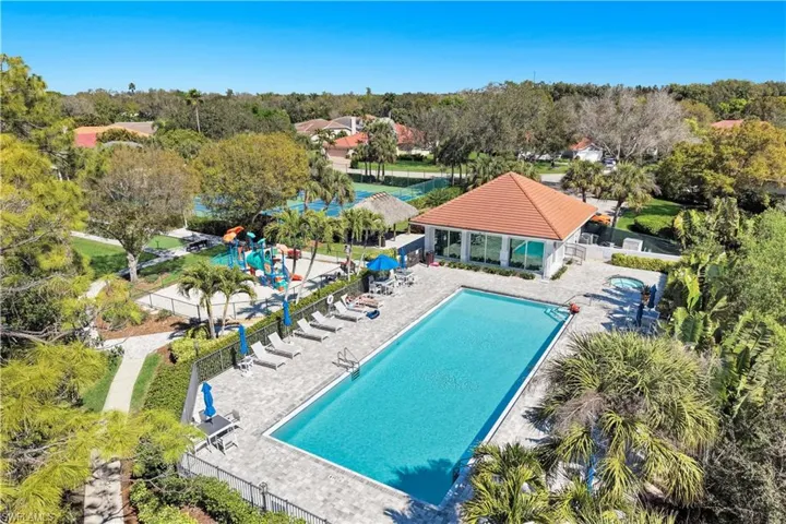 Community pool with a patio and view of wooded area
