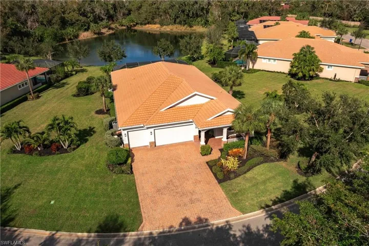 Aerial view of home with large paved driveway, 3 car garage and lake view and preserve in background. Largest lot in neighborhood.