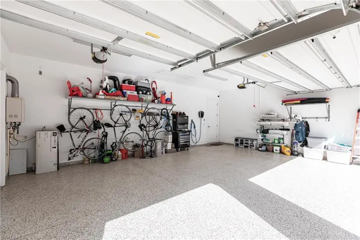 Garage featuring tankless water heater and plenty of room for cars, golf cart or storage.