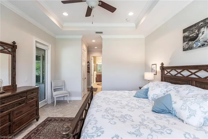 Tiled primary bedroom featuring a tray ceiling and ensuite bath.