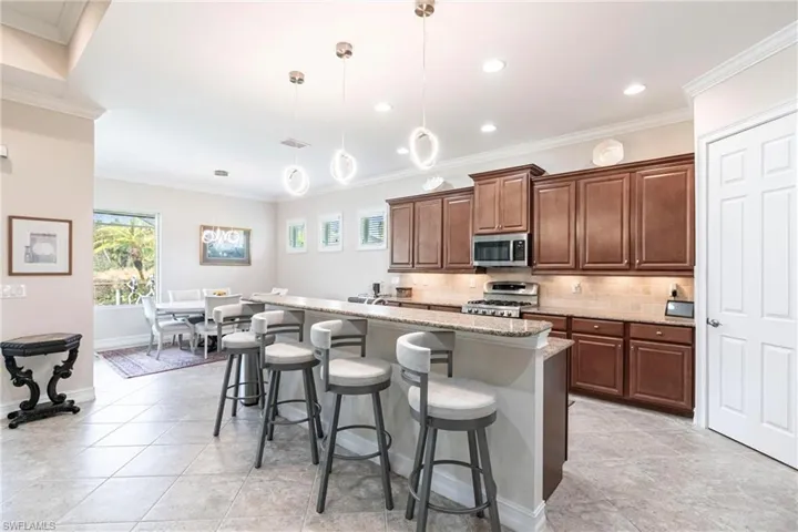 Kitchen with a kitchen bar, a kitchen island with sink, decorative light fixtures and granite countertops