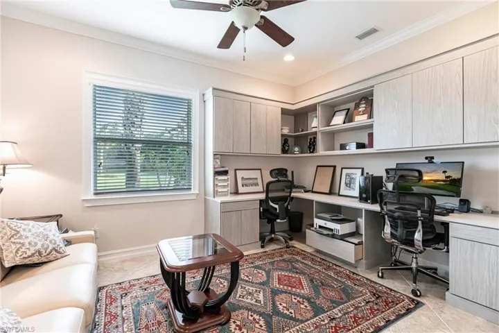 Huge Den with built in cabinets and desks, ceiling fan, crown molding, and tile floor.