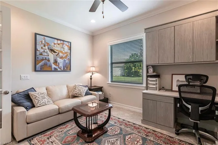 Home office featuring built in desk, double doors, ceiling fan, and crown molding