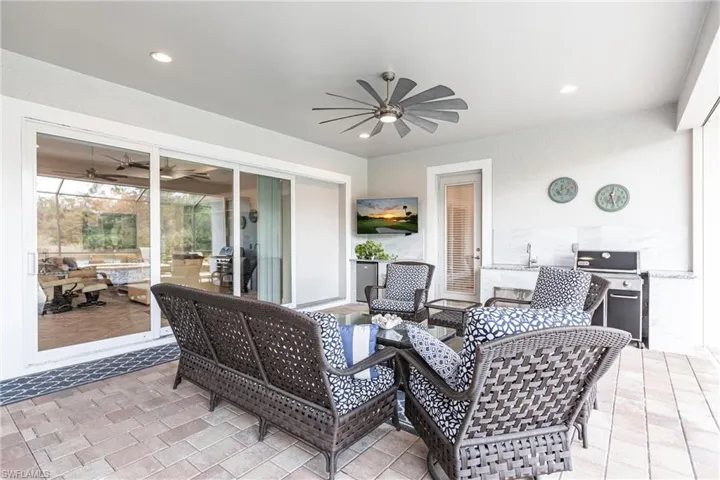 Extended Lanai area featuring a full outdoor kitchen, ceiling fan and plenty of under roof sitting area.