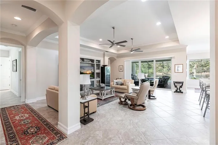 Living room featuring diagonal tile floor, a tray ceiling, ceiling fan, and crown molding