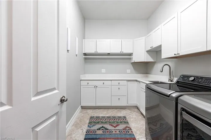 Clothes washing area with cabinets, hanging bars and sink