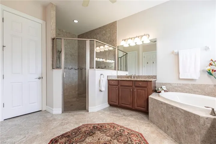 Bathroom with ceiling fan, walk-in shower with separate bathtub.