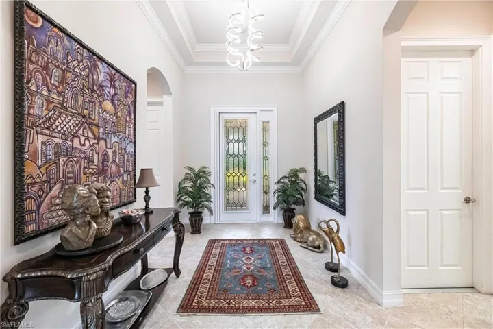 Tiled foyer with a raised ceiling and ornamental molding