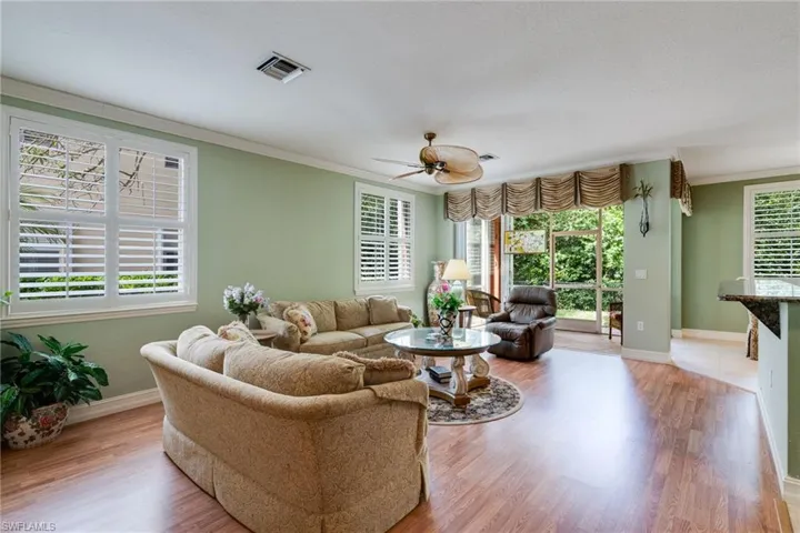 Living room with crown molding, light wood-style flooring, and a ceiling fan