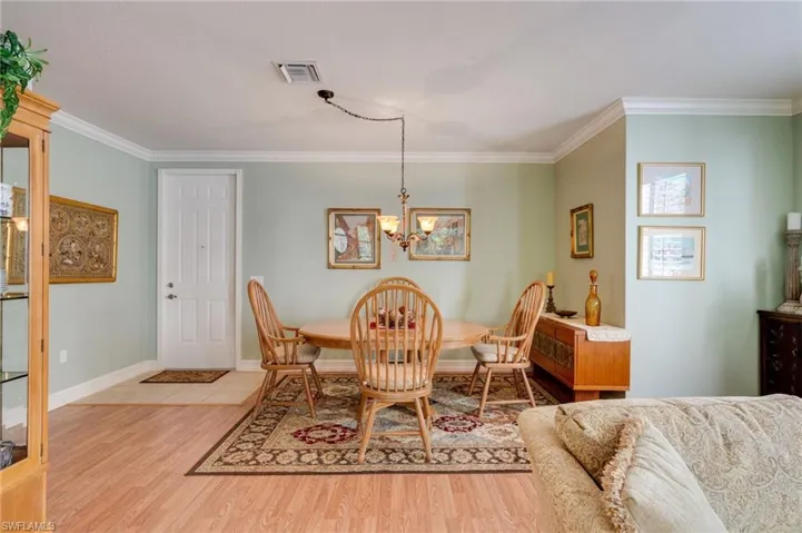 Dining space featuring light wood-style flooring, hanging lights, and ornamental molding