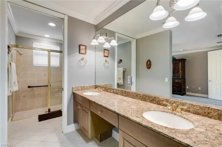 Full bathroom featuring double vanity, ornamental molding, a shower stall, light tile patterned floors, and recessed lighting
