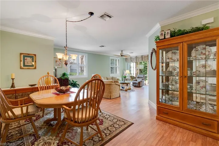 Dining area with ornamental molding, light wood-style flooring, ceiling fan, and hanging lights