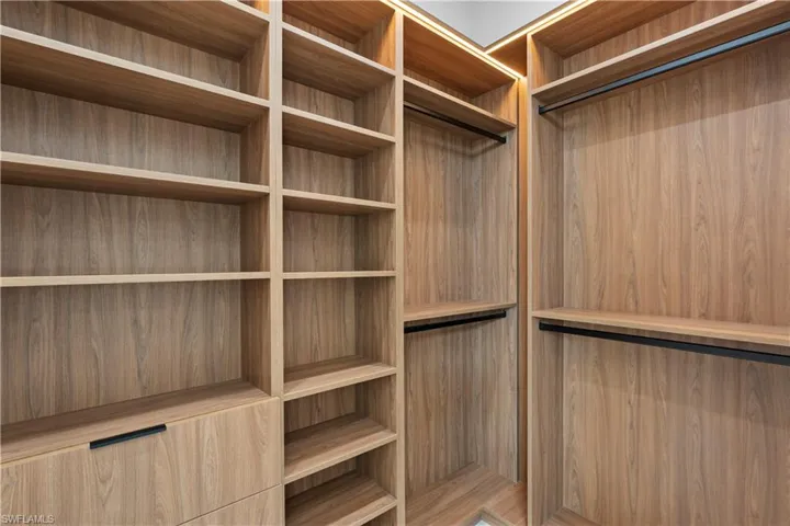 Built-in closet system featuring wood-finish shelving, integrated hanging rods, and a drawer with a matte black pull