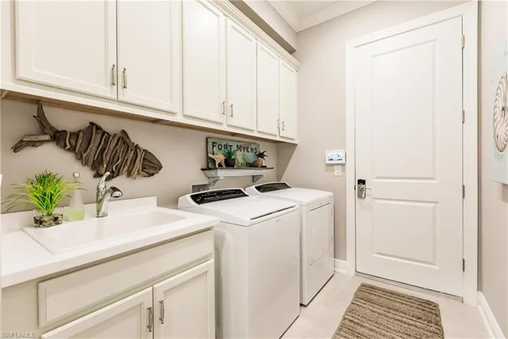 THE LAUNDRY ROOM HAS PLENTY OF WHITE CABINETS & A SINK!