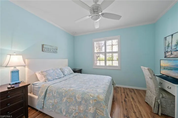 Wood-finish flooring, multi-pane window with interior shutters, and ceiling fan with integrated lighting