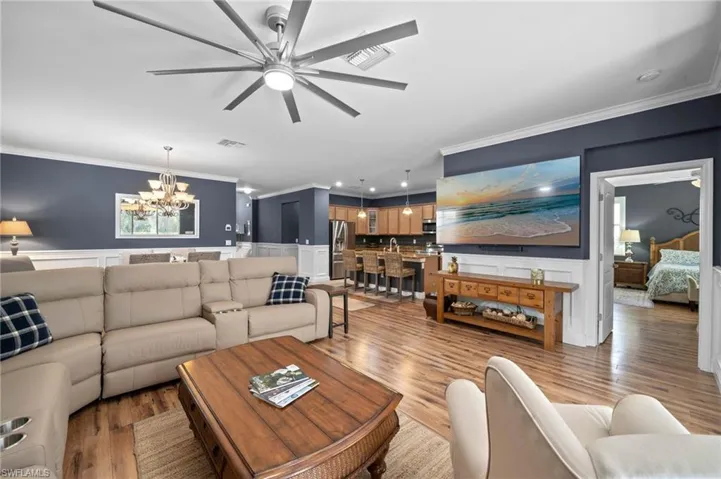 Large-scale multi-blade ceiling fan, wood-finish flooring, wainscoting, and crown molding