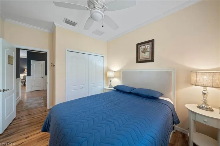 Wood-finish flooring, ceiling fan with integrated lighting, bi-fold closet doors, and crown molding