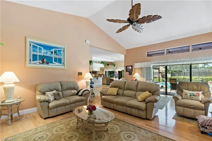 Living room with high vaulted ceiling, ceiling fan, and hardwood / wood-style floors