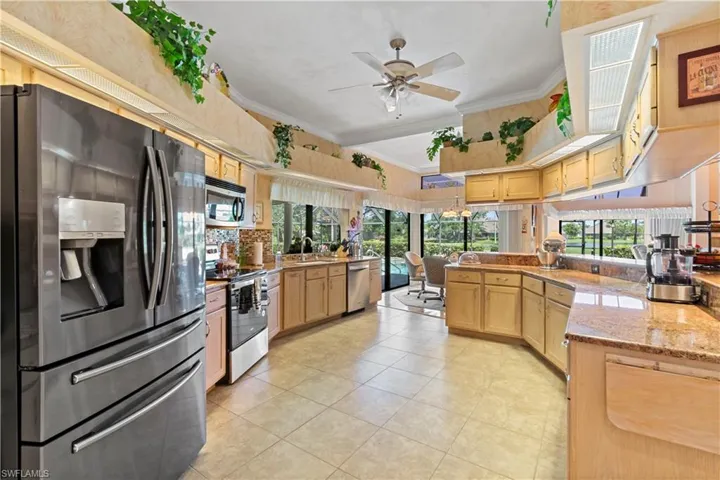 Kitchen featuring light brown cabinets, ceiling fan, ornamental molding, appliances with stainless steel finishes, and light tile floors