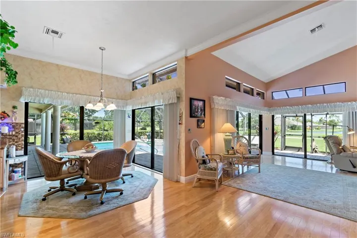 Dining area with high vaulted ceiling, light hardwood / wood-style flooring, and a notable chandelier