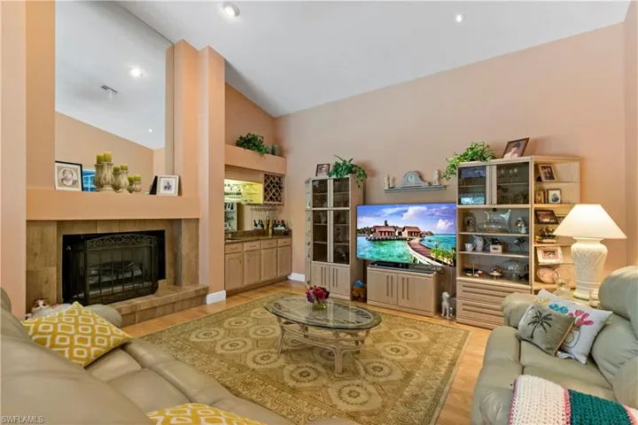 Living room featuring high vaulted ceiling, a tiled fireplace, and light hardwood / wood-style flooring