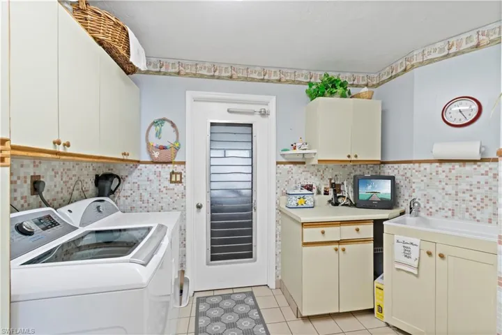 Laundry room with independent washer and dryer, light tile flooring, hookup for an electric dryer, sink, and cabinets