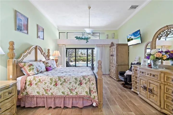 Bedroom featuring wood-type flooring, access to exterior, and crown molding