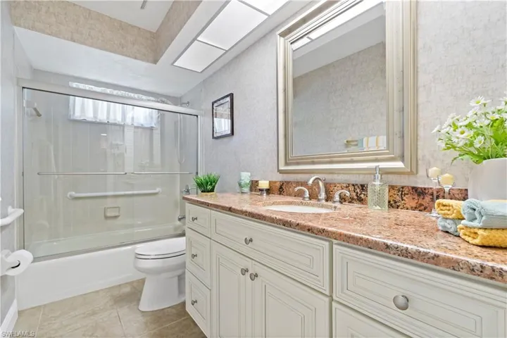 Full bathroom featuring shower / bath combination with glass door, vanity, toilet, and tile floors