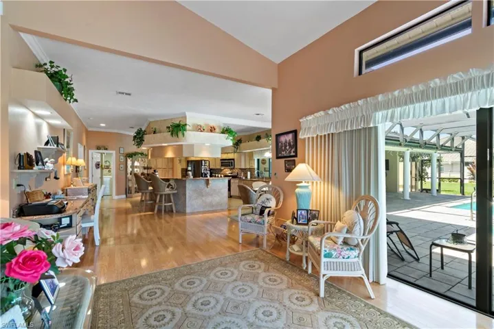 Living room with vaulted ceiling, ornamental molding, and light wood-type flooring