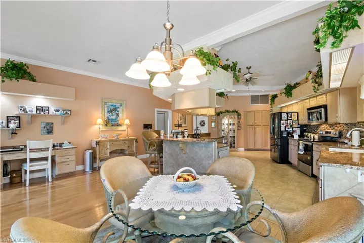 Tiled dining space featuring ceiling fan with notable chandelier, sink, and ornamental molding