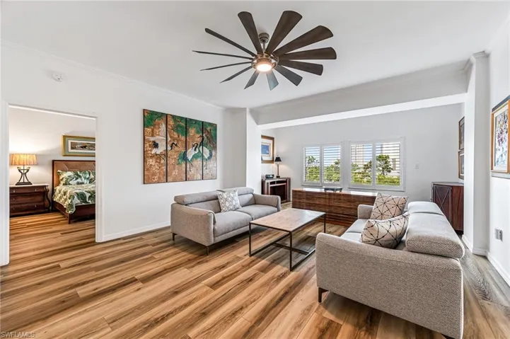 Living room with ceiling fan, wood-type flooring, and ornamental molding