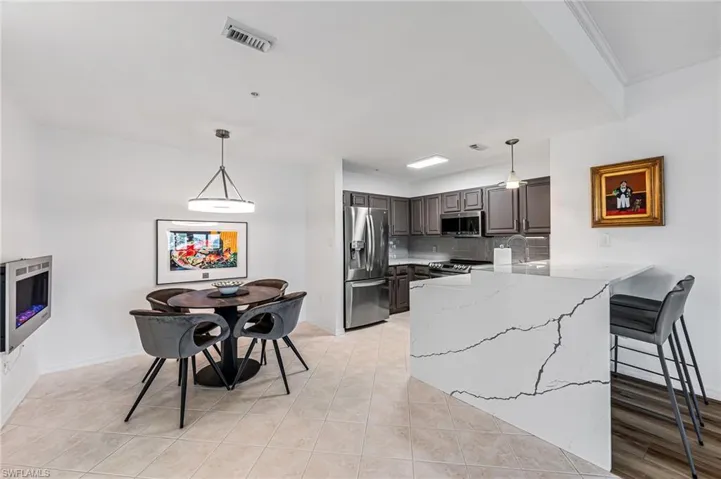 Kitchen with kitchen peninsula, light stone counters, stainless steel appliances, decorative backsplash, and pendant lighting