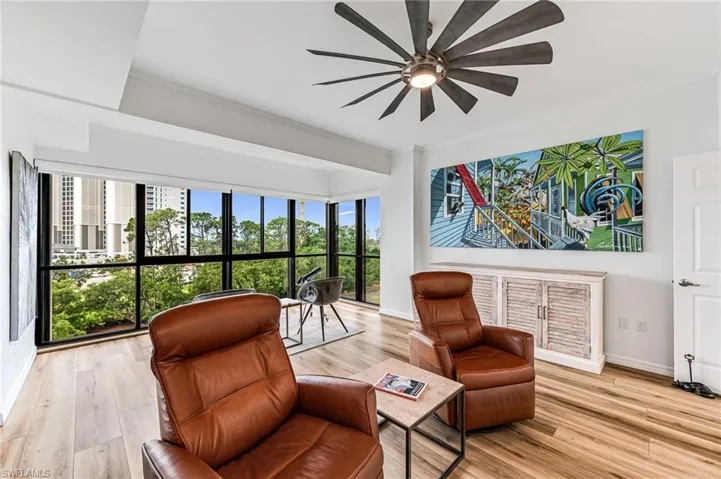 Den with ceiling fan and light wood-type flooring