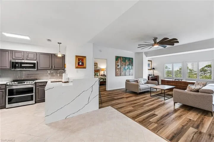 Kitchen with light hardwood / wood-style flooring, ceiling fan, stainless steel appliances, decorative backsplash, and pendant lighting