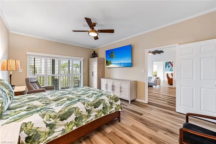 Bedroom featuring light hardwood / wood-style floors, ornamental molding, and ceiling fan