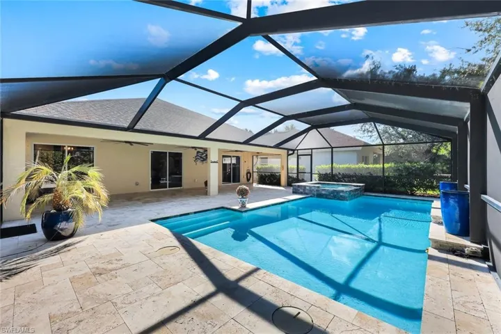View of pool featuring a sunroom, screen enclosure, a patio area, a ceiling fan, and a pool with connected hot tub