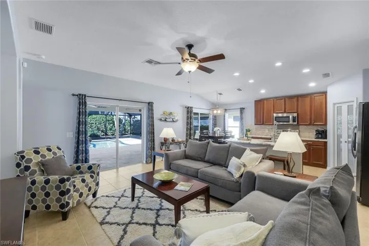 Living room featuring light tile flooring, a ceiling fan, recessed lighting, and lofted ceiling