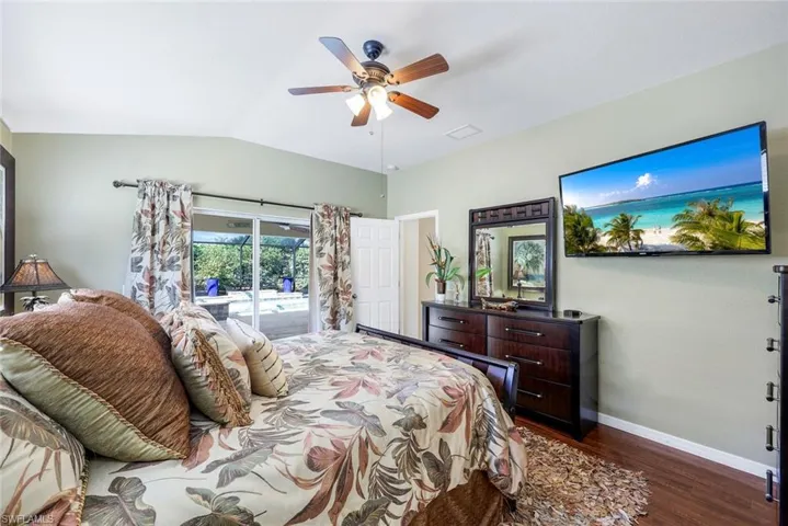 Bedroom featuring access to exterior, laminate floors, vaulted ceiling, and ceiling fan