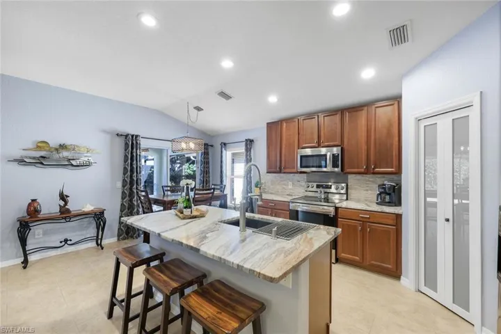 Kitchen with walnut cabinets, a breakfast bar, granite countertops, decorative backsplash, and lofted ceiling