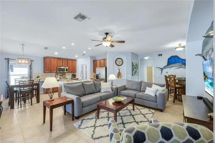 Living room with recessed lighting, light tile floors, ceiling fan, and arched walkways