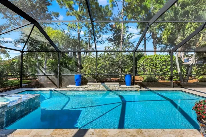 View of pool with a pool with connected hot tub, screen enclosure