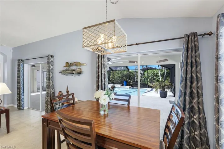 Dining area with light tile floors, and a chandelier, view to the huge pool area