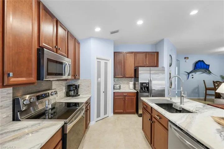 Kitchen featuring stainless steel appliances, backsplash, granite counters, walnut cabinets, and recessed lighting